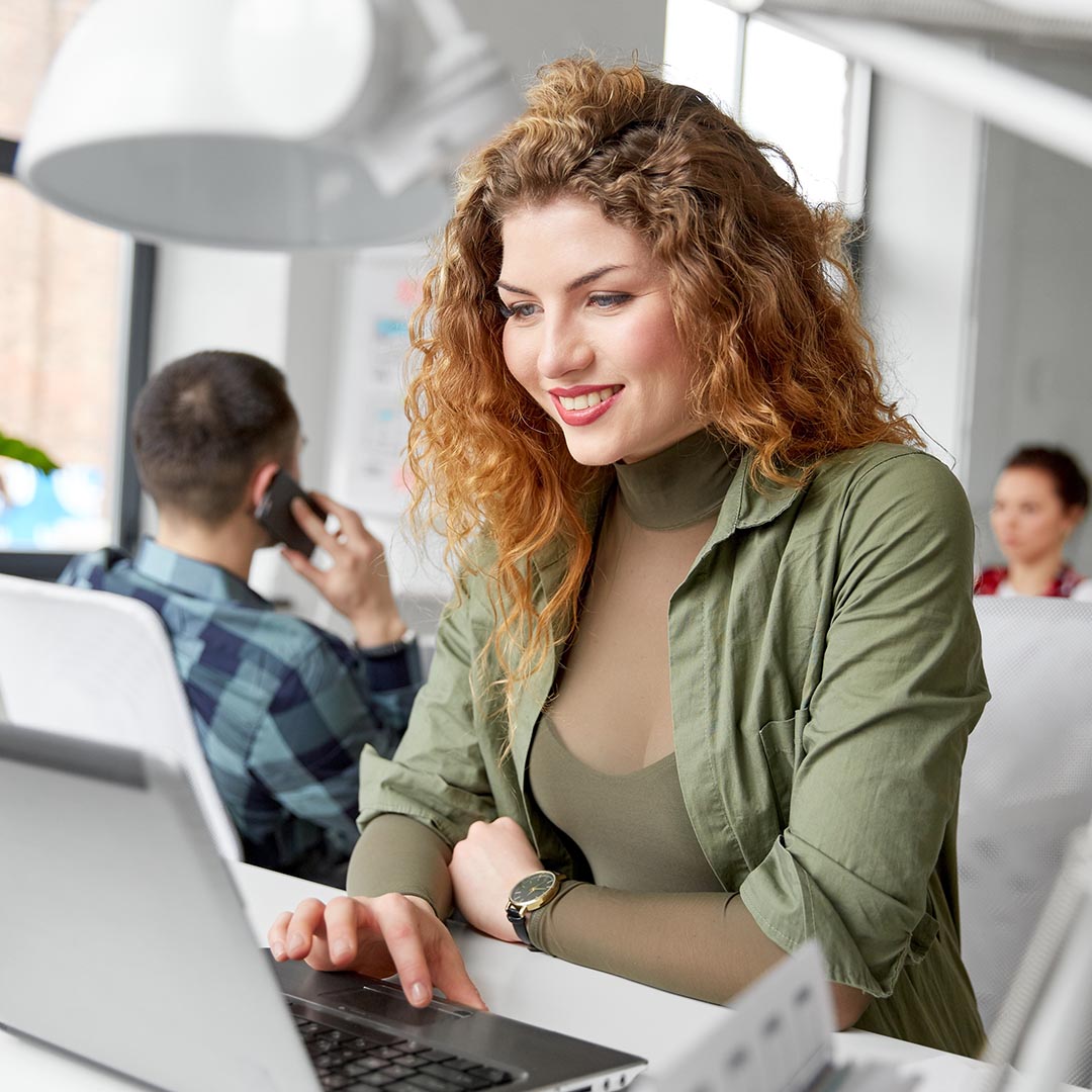 smiling woman using a laptop at work
