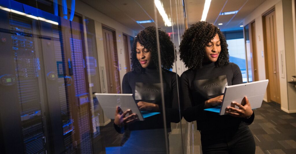 woman holds laptop standing outside server room
